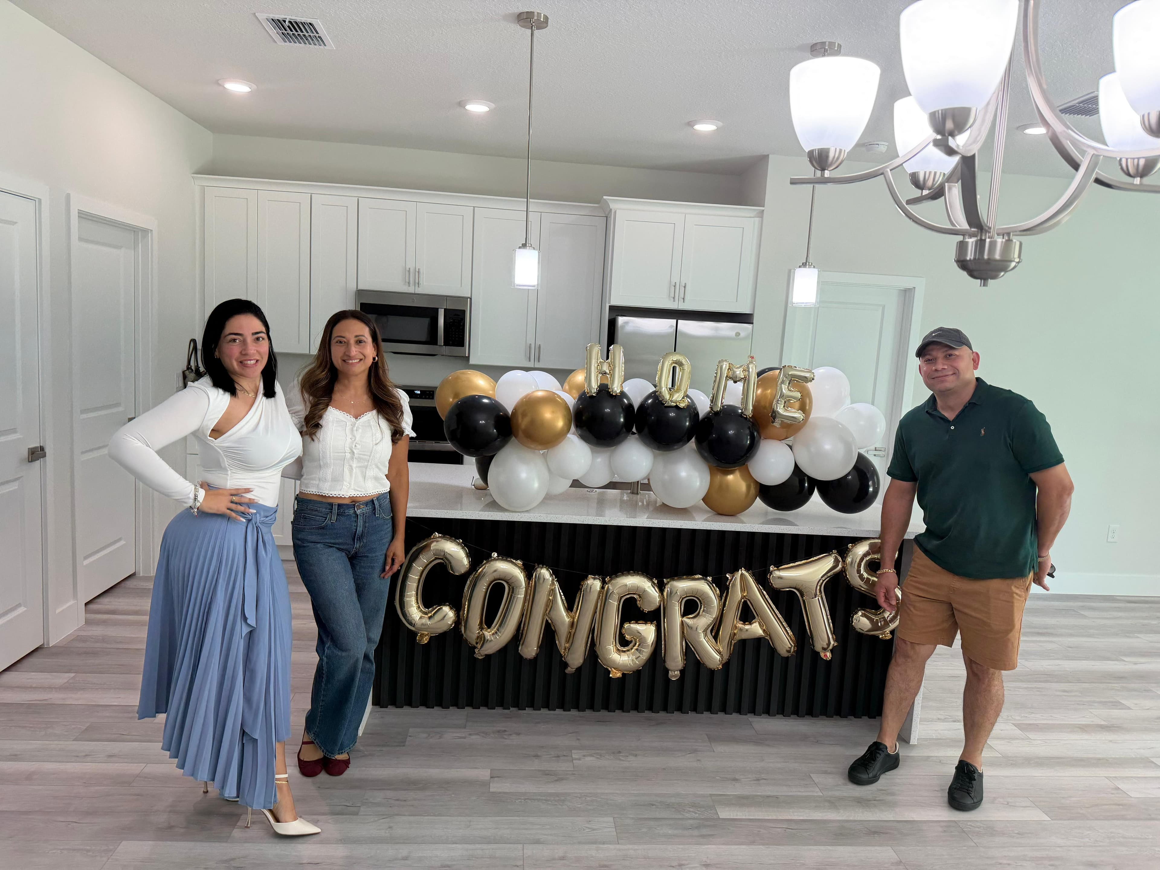 Lazara Diaz Tampa Bay Realtor celebrating with clients in front of CONGRATS and HOME balloon display